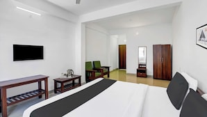 Una habitación de hotel con una cama, un escritorio, una silla, un televisor y un armario.
