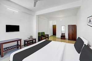 Una habitación de hotel con una cama, un escritorio, una silla, un televisor y un armario.