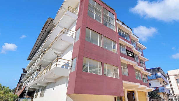 Un edificio de varios pisos con fachada roja y blanca, balcones y un cartel que indica que es una casa adosada.