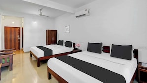 Una habitación de hotel con dos camas, un armario de madera, un escritorio y un ventilador de techo.