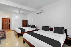 Una habitación de hotel con dos camas, un armario de madera, un escritorio y un ventilador de techo.
