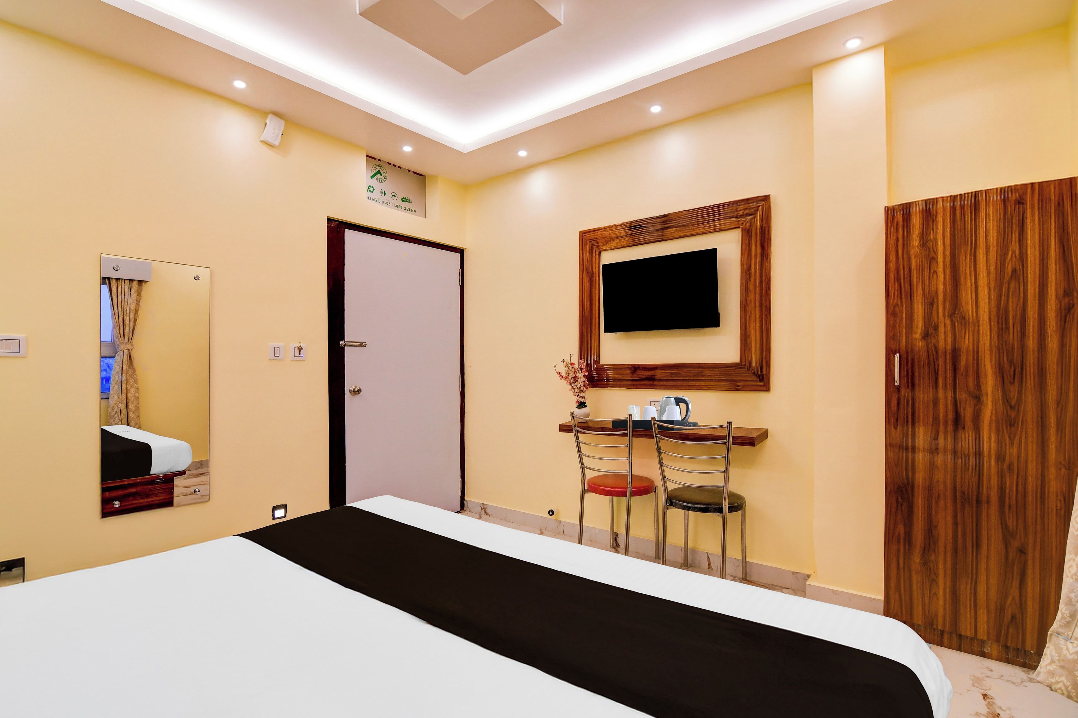 Ein Hotelzimmer mit einem Bett, einem Schreibtisch mit Stuhl, einem an der Wand montierten Fernseher und einem Holzschrank.