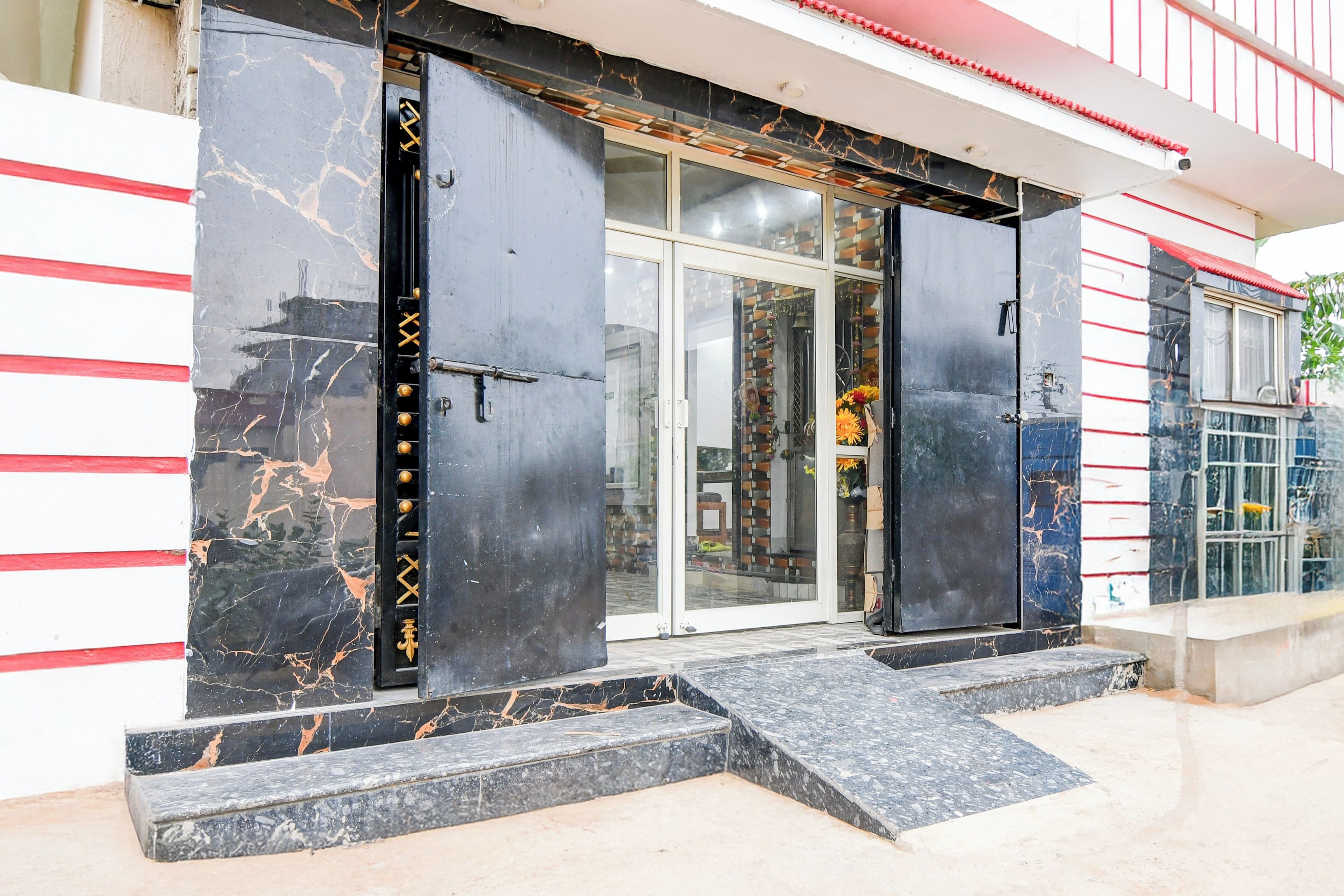 Una entrada de edificio con puerta de cristal y portón de metal negro.