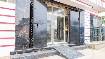 Una entrada de edificio con puerta de cristal y portón de metal negro.