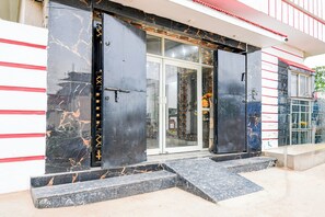 Una entrada de edificio con puerta de cristal y portón de metal negro.