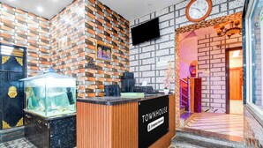 A reception area with a wooden reception desk, a fish tank, and a wall with a brick pattern. - Townhouse Puri Sea Beach (Puri)