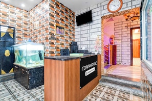 Et receptionområde med en træreception, en fisketank og en væg med murstensmønster.