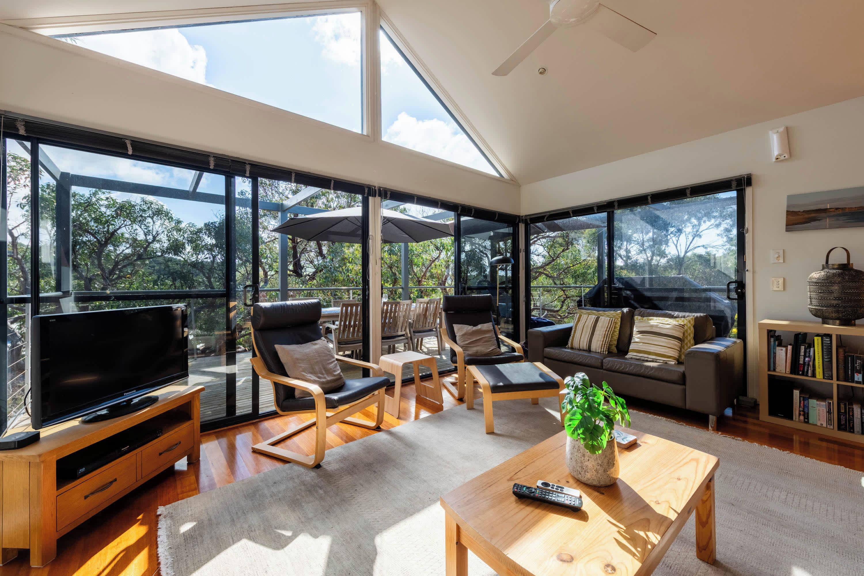 A spacious living room with a large TV, comfortable seating, and a view of the outdoors.