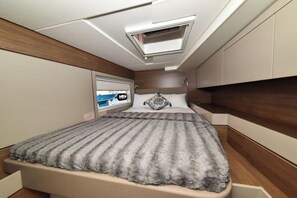 Ein gemütliches Schlafzimmer mit Bett, Fenster und integriertem Fernseher.