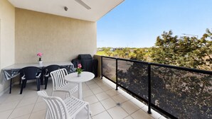 Ein Balkon mit Tisch und Stühlen, einem Deckenventilator und Blick auf die Umgebung.