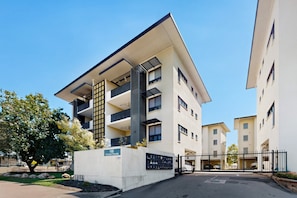 A modern multi-story building with a flat roof, large windows, and a gated entrance. - Peaceful 2-bed Apartment With Private BBQ Balcony (Darwin)