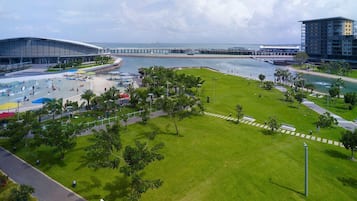 A coastal area with a large stadium, a beach with umbrellas, and a pier.