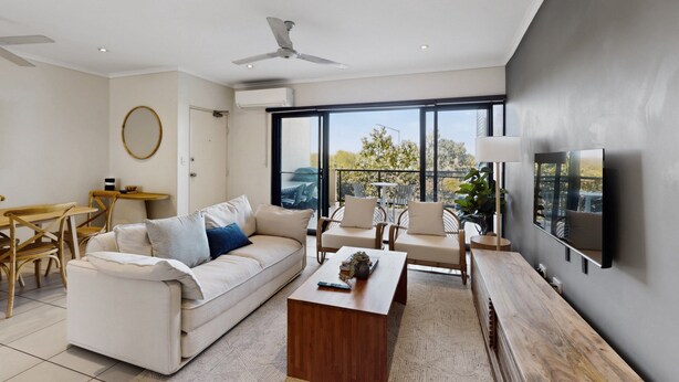 Ein modernes Wohnzimmer mit Sofa, Couchtisch und Sesseln, ein Essbereich mit Tisch und Stühlen und ein großes Fenster mit Blick.