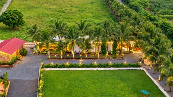 A hotel with a red-roofed building, a paved courtyard, and a well-maintained lawn.