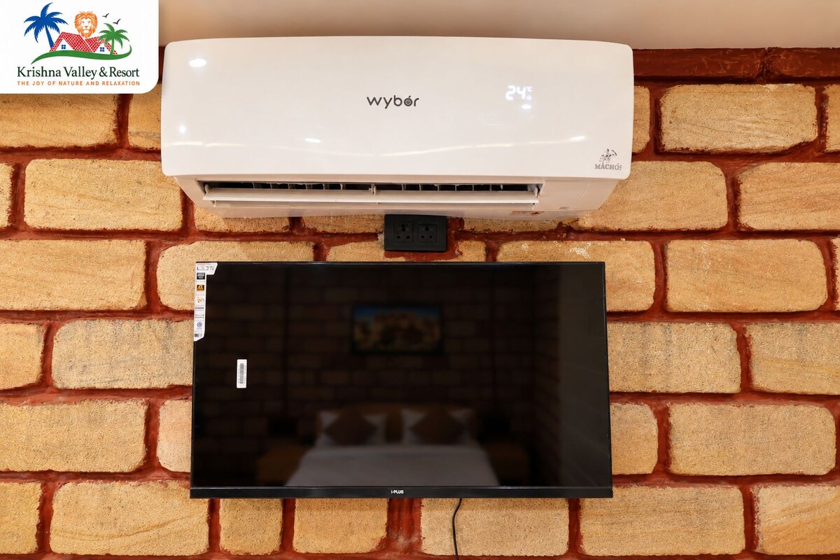 A white air conditioning unit mounted on a brick wall with a television screen displaying a blurred interior scene.