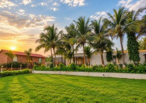 A hotel with a brick facade, palm trees, and a well-maintained lawn.