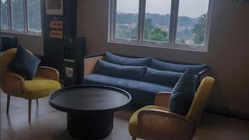 Un espacio de descanso con sofá y sillones, una mesa redonda y vistas a través de amplios ventanales.