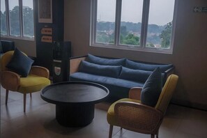 Un espacio de descanso con sofá y sillones, una mesa redonda y vistas a través de amplios ventanales.