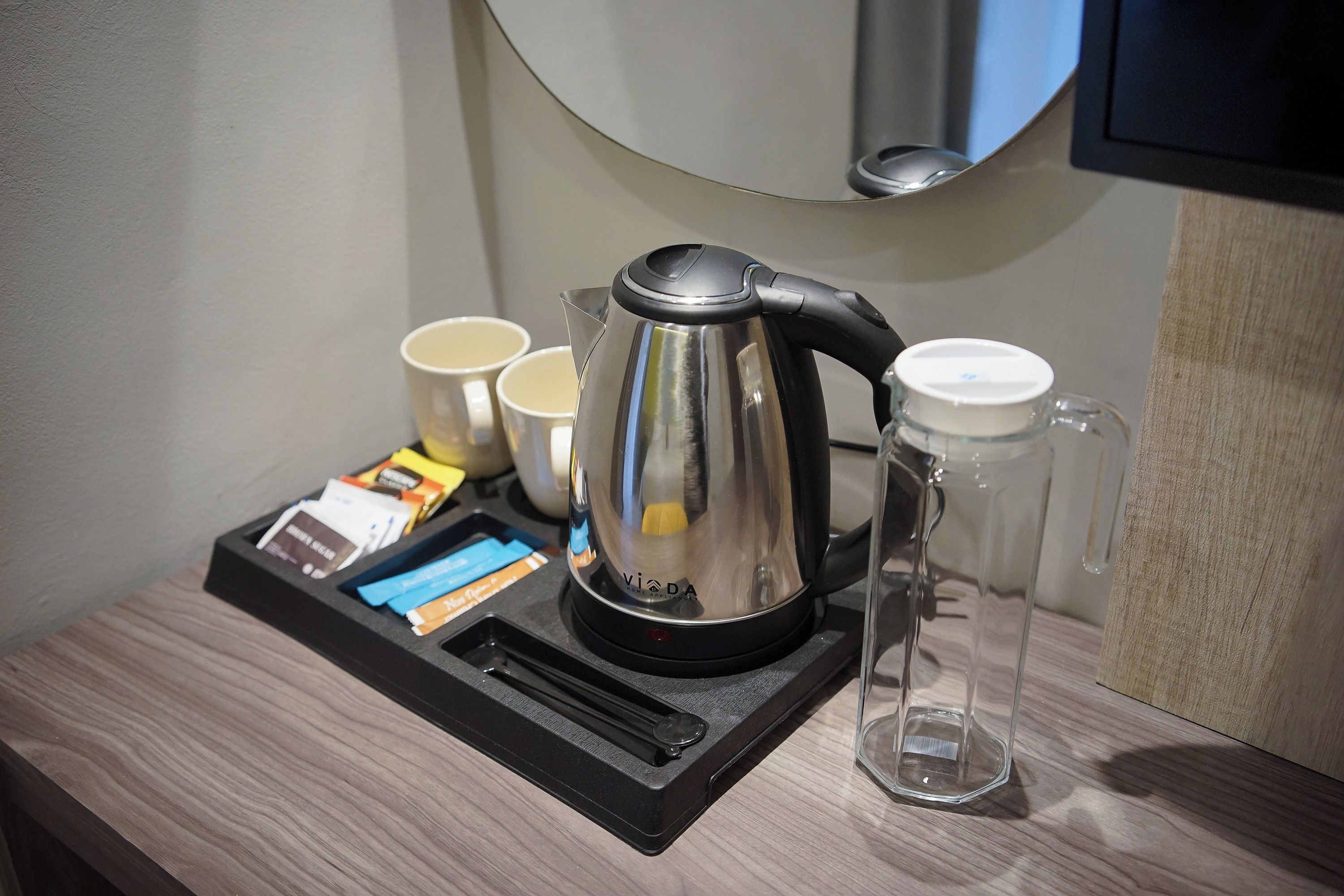 Une machine à café sur un plateau, accompagnée d’une tasse, d’un verre et de quelques en-cas emballés.