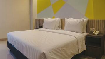 Una habitación de hotel con una cama grande, una mesita de noche con un teléfono y una pared con diseño geométrico.