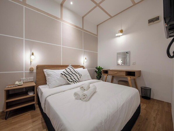 A modern hotel room with a large bed, bedside table, and a desk with a mirror.