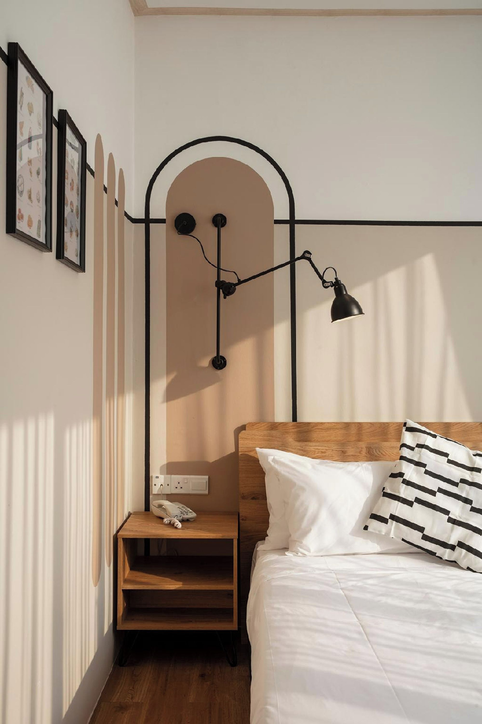Un dormitorio con cabecera de madera, mesita de noche con teléfono y lámpara de pared.