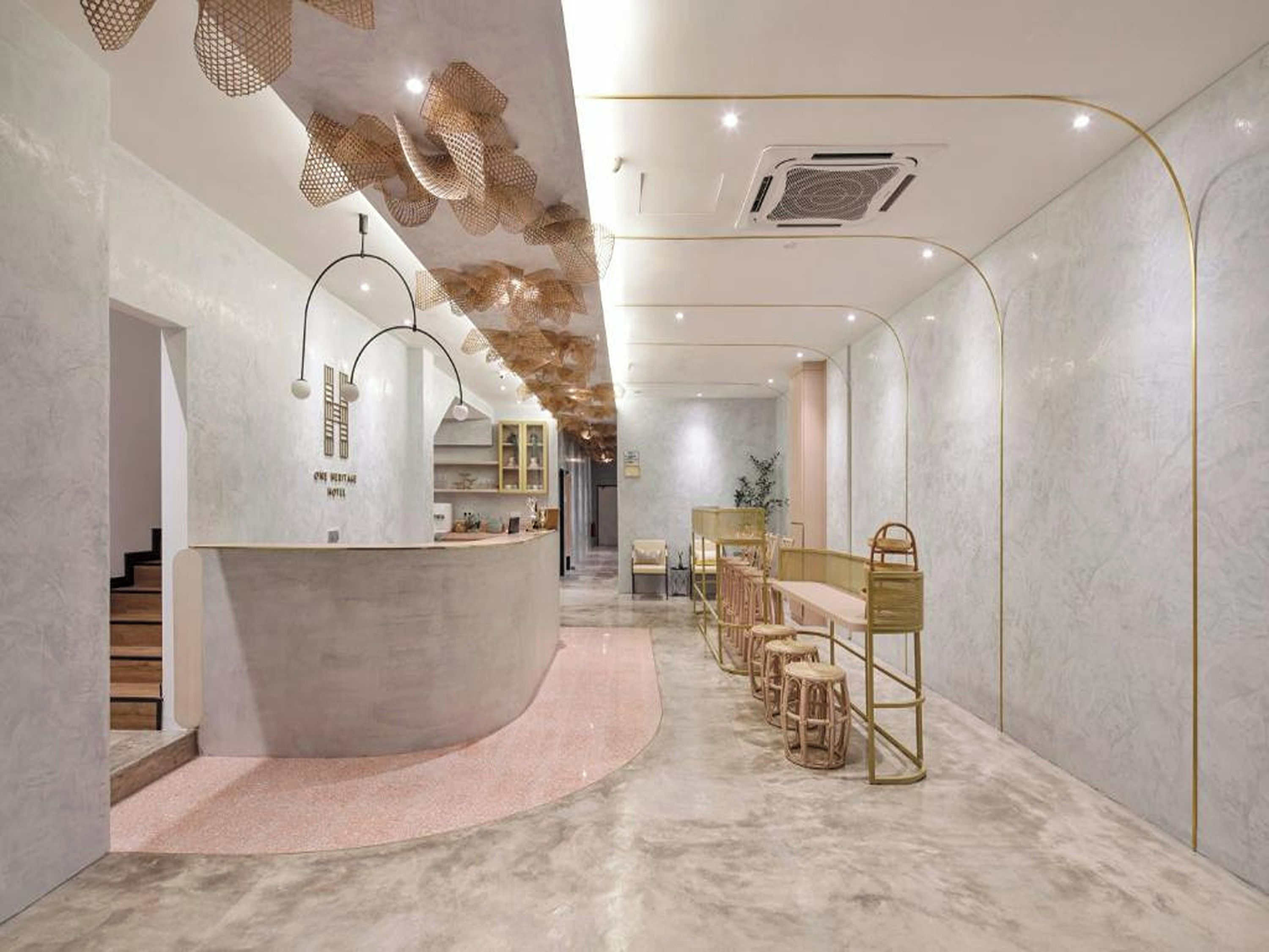 Un vestíbulo de hotel con un mostrador de recepción curvo, una zona de estar con taburetes de madera y un suelo de mármol.