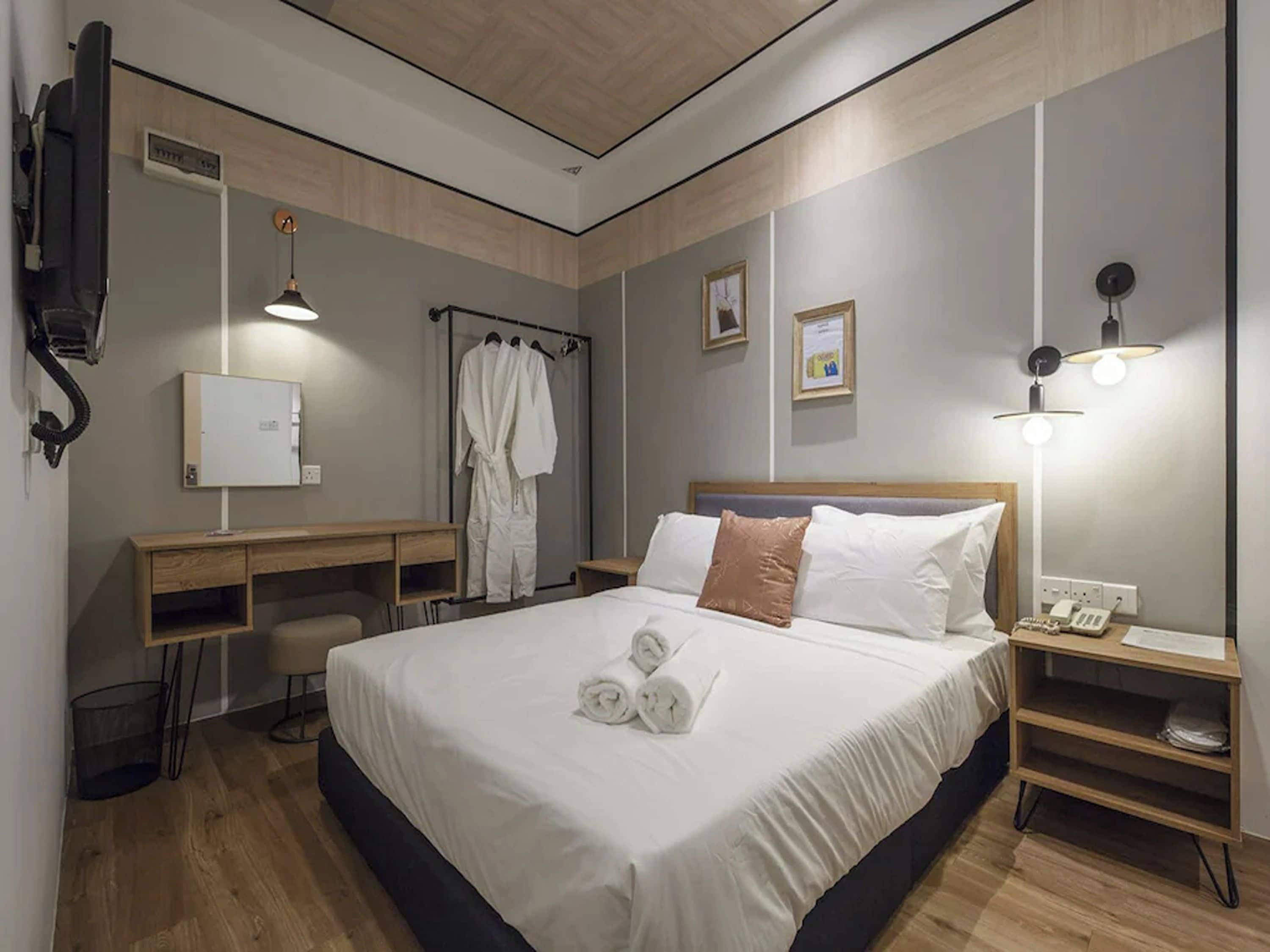 Ein Hotelzimmer mit Bett, Nachttisch, Schreibtisch und einer Duschkabine.