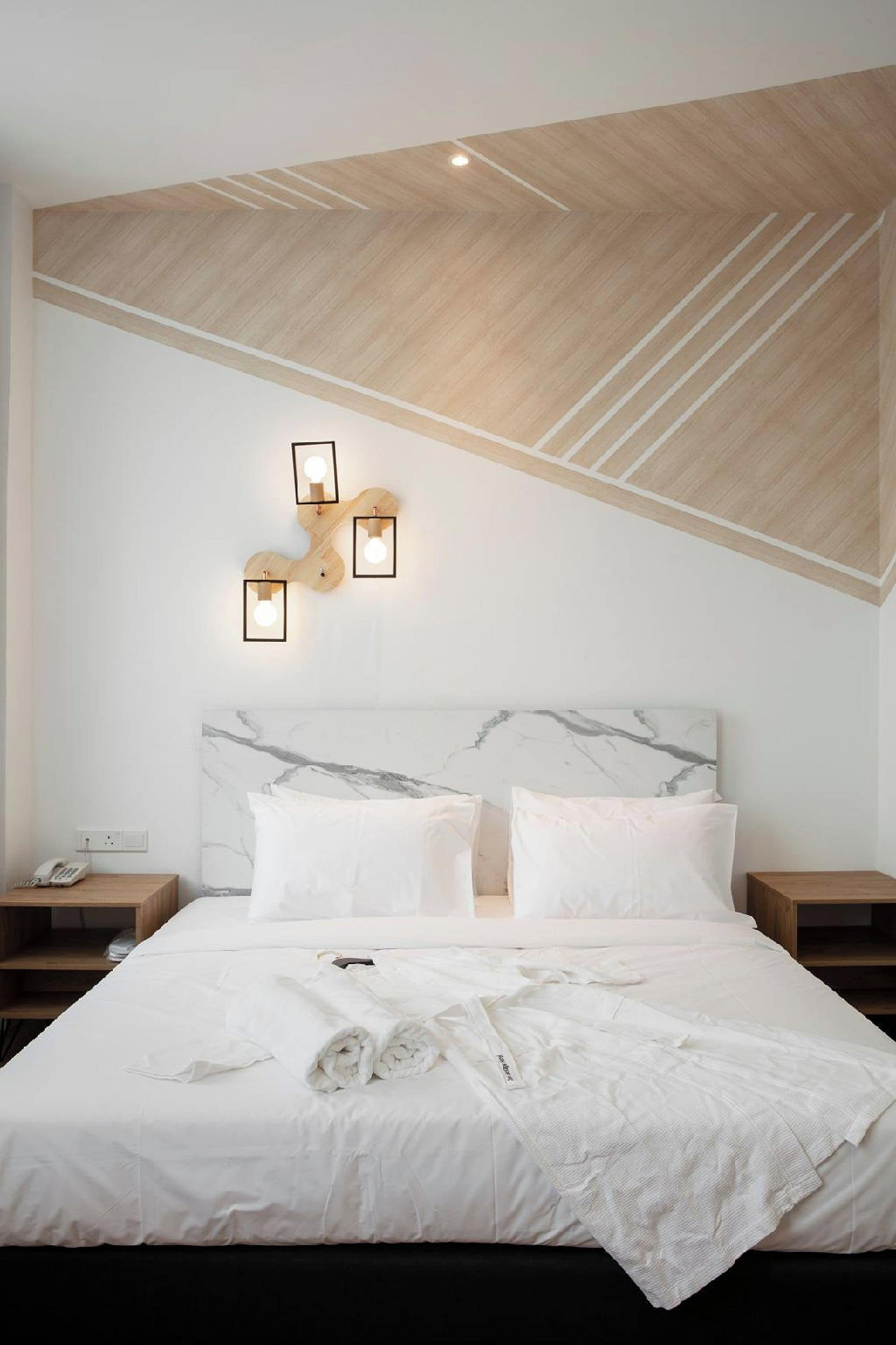 A modern bedroom with a wooden ceiling, a marble headboard, and bedside tables with lamps.