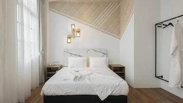 A modern bedroom with a bed, bedside tables, a wall-mounted light fixture, and a clothing rack.