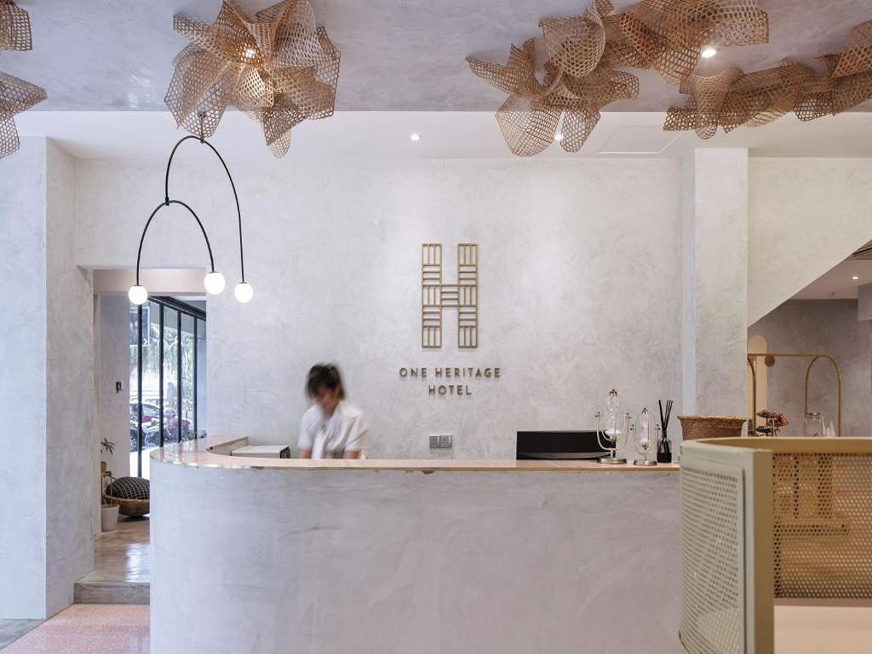 Ein moderner Hotelrezeptionstresen mit einer Rezeptionistin und einem Logo an der Wand.