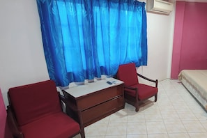 A room with a bed, a desk with drawers, two red chairs, and a blue curtain. - Hotel Medan Kidd (Ipoh)