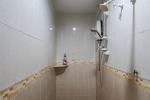 A small, tiled shower room with a handheld showerhead, a wall-mounted faucet, and a soap dispenser on a shelf. - Hotel Medan Kidd (Ipoh)