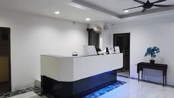 Un mostrador de recepción de diseño moderno, un ventilador de techo y una pequeña planta en maceta.
