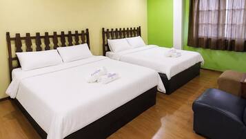 Habitación de hotel con dos camas, cada una con ropa blanca y almohadas, y un par de toallas enrolladas con el logotipo del hotel.