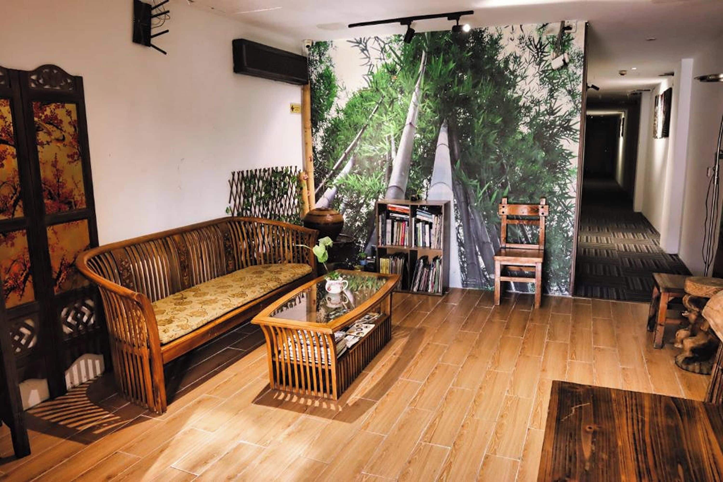A room with a wooden floor, a sofa, a coffee table, a bookshelf, and a large wall mural.