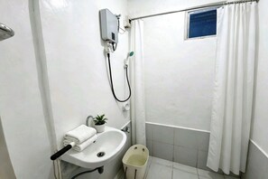 A small bathroom with a sink, a toilet, a shower, and a window.