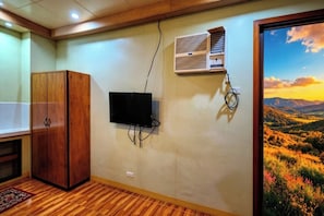 Una habitación con armario de madera, televisor montado, unidad de aire acondicionado y ventana con vistas panorámicas.