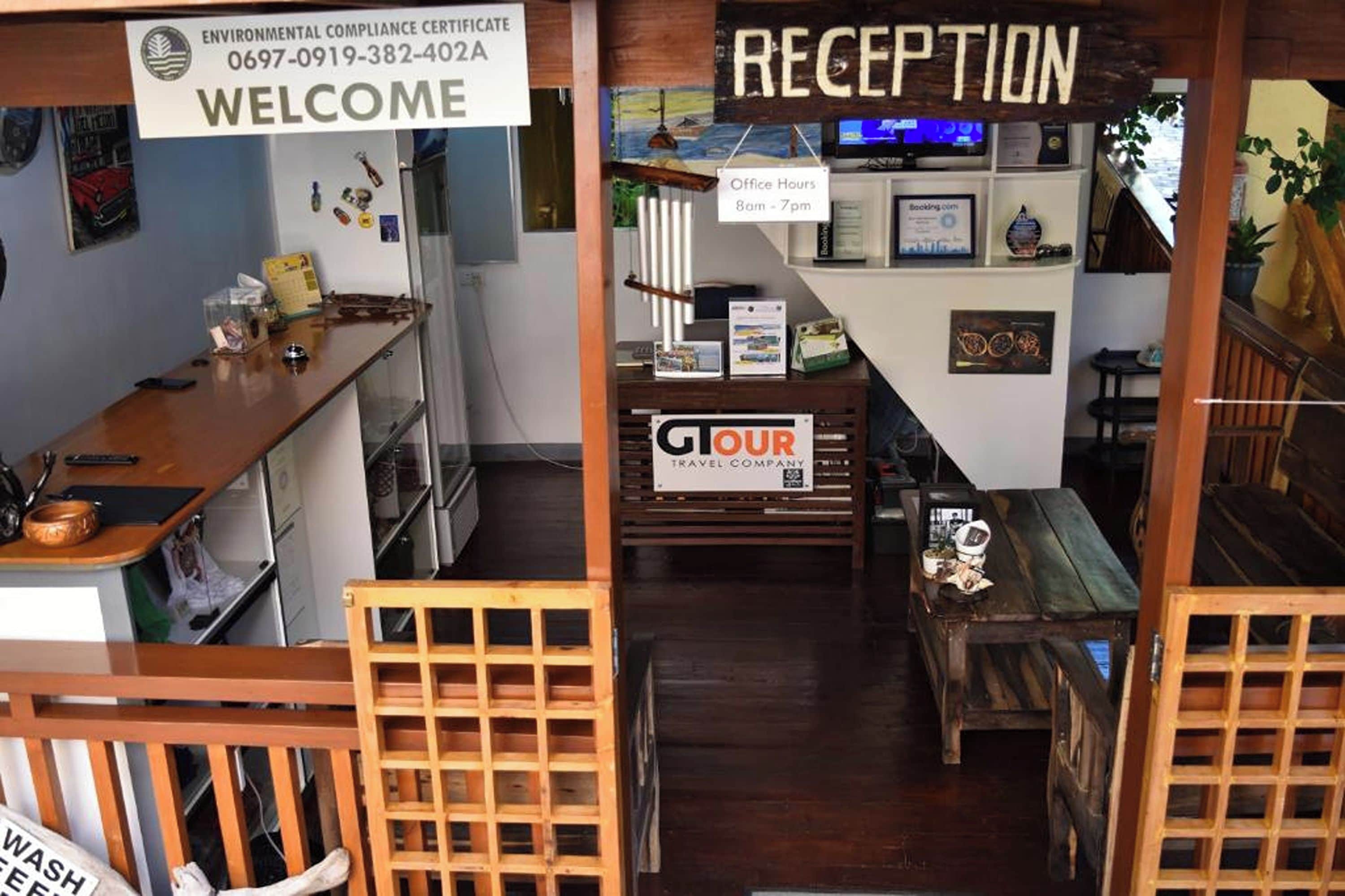 Zona de recepción con un mostrador de madera, un cartel de 'WELCOME' y un cartel de 'RECEPTION'.