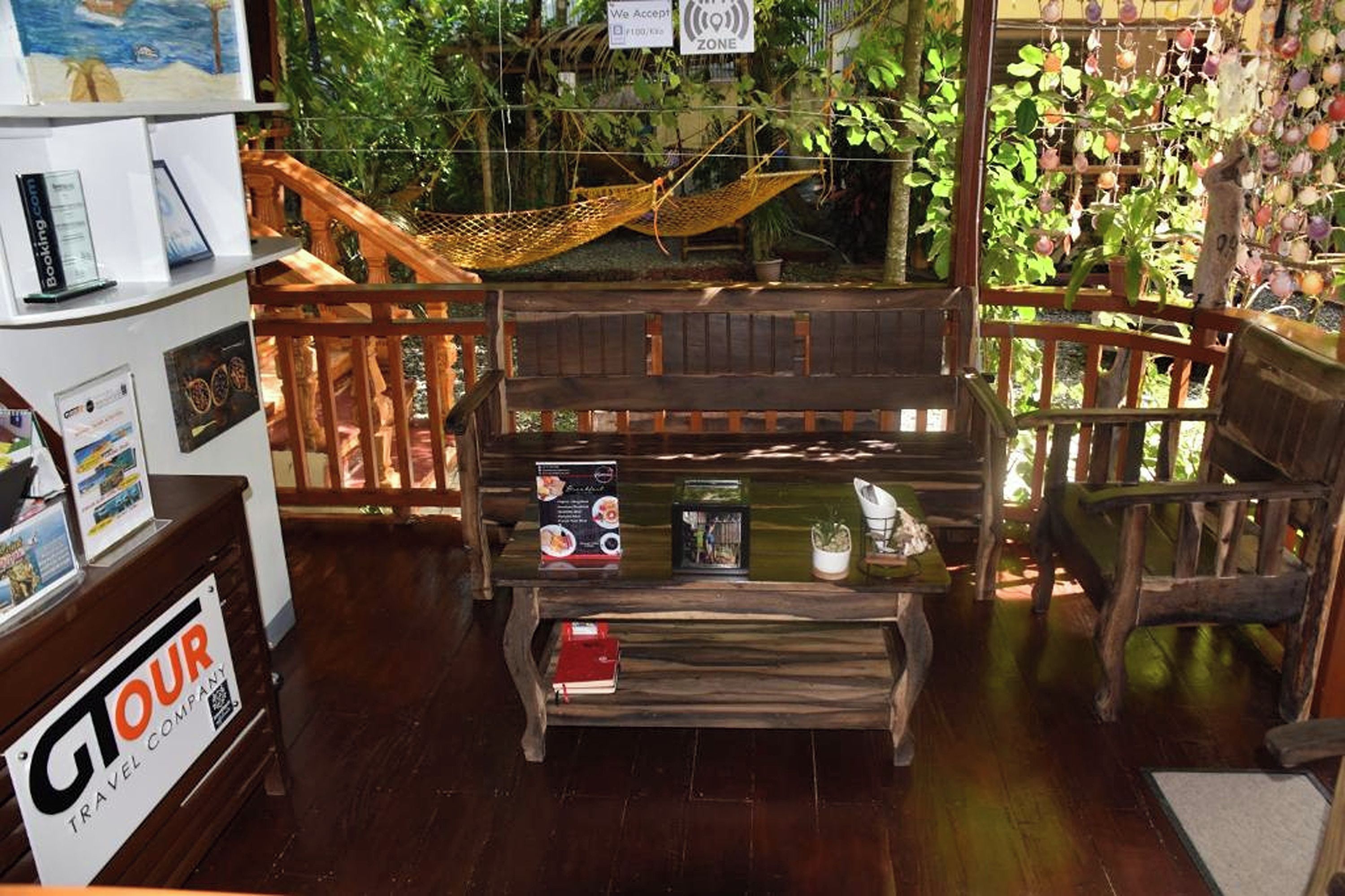 Una habitación acogedora con una hamaca, muebles de madera y vistas a abundante vegetación.
