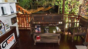 Una habitación acogedora con una hamaca, muebles de madera y vistas a abundante vegetación.