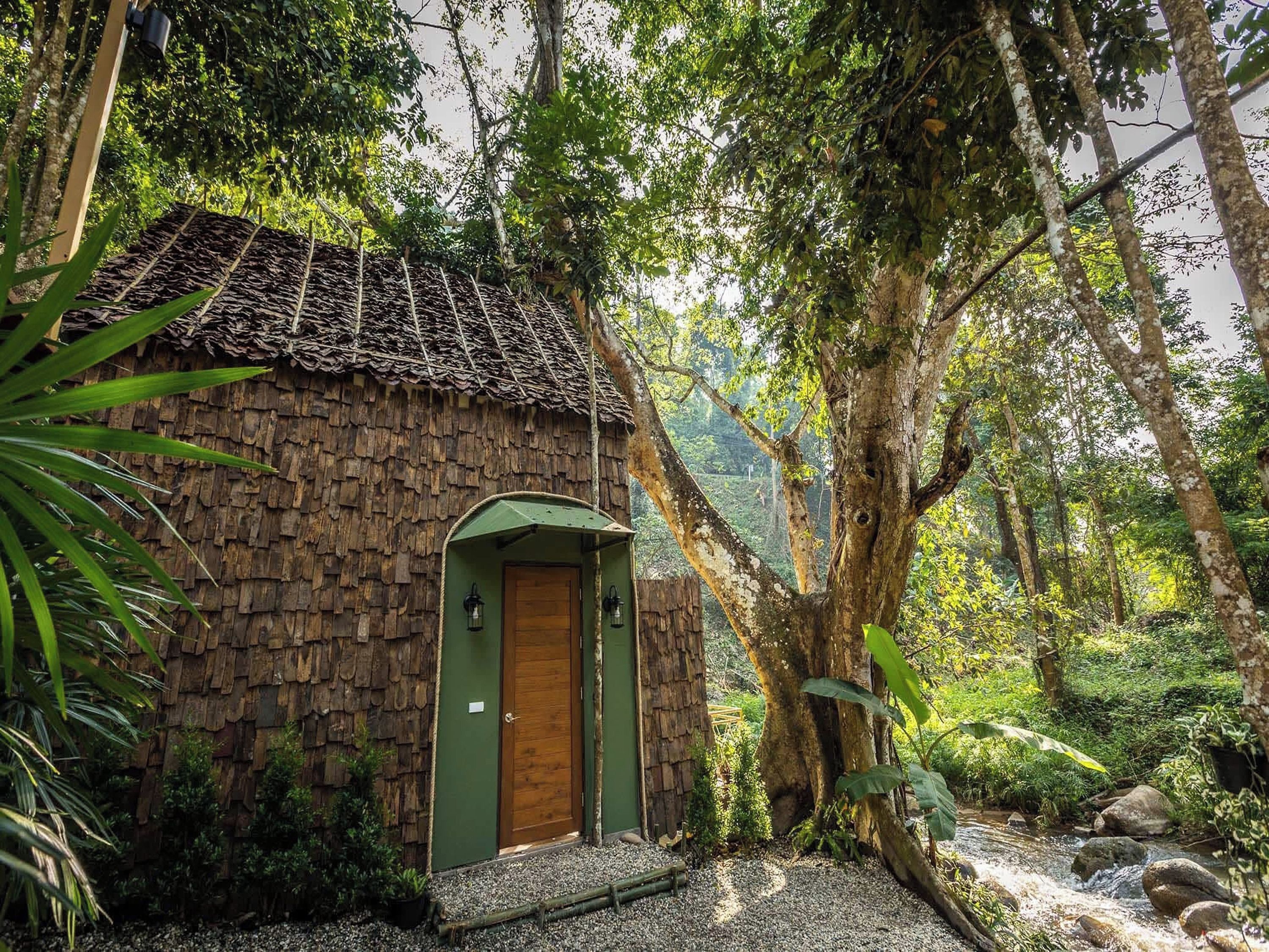 A rustic hut with a thatched roof, a wooden door, and a small porch area.