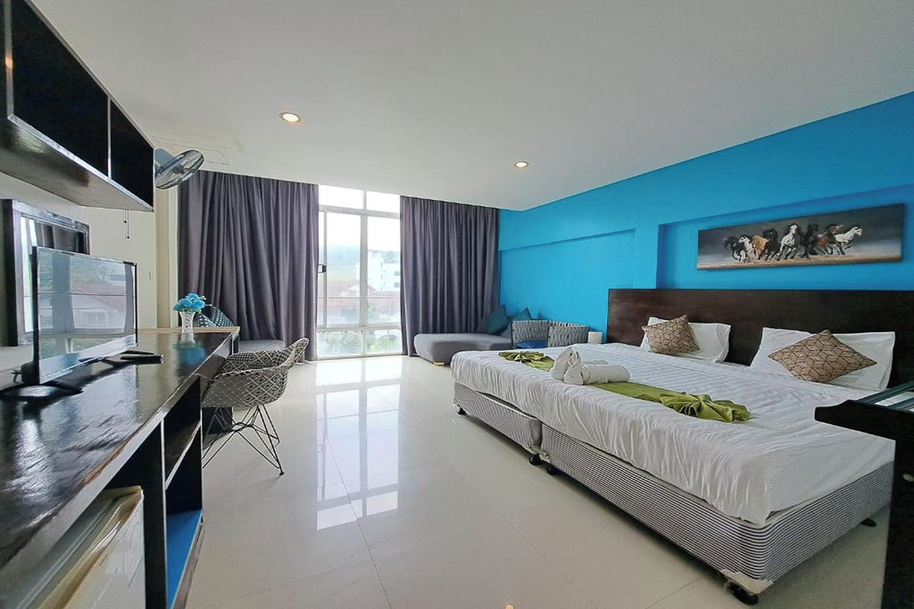 Una habitación de hotel con una cama, un escritorio, una silla, un televisor y un cuadro en la pared.