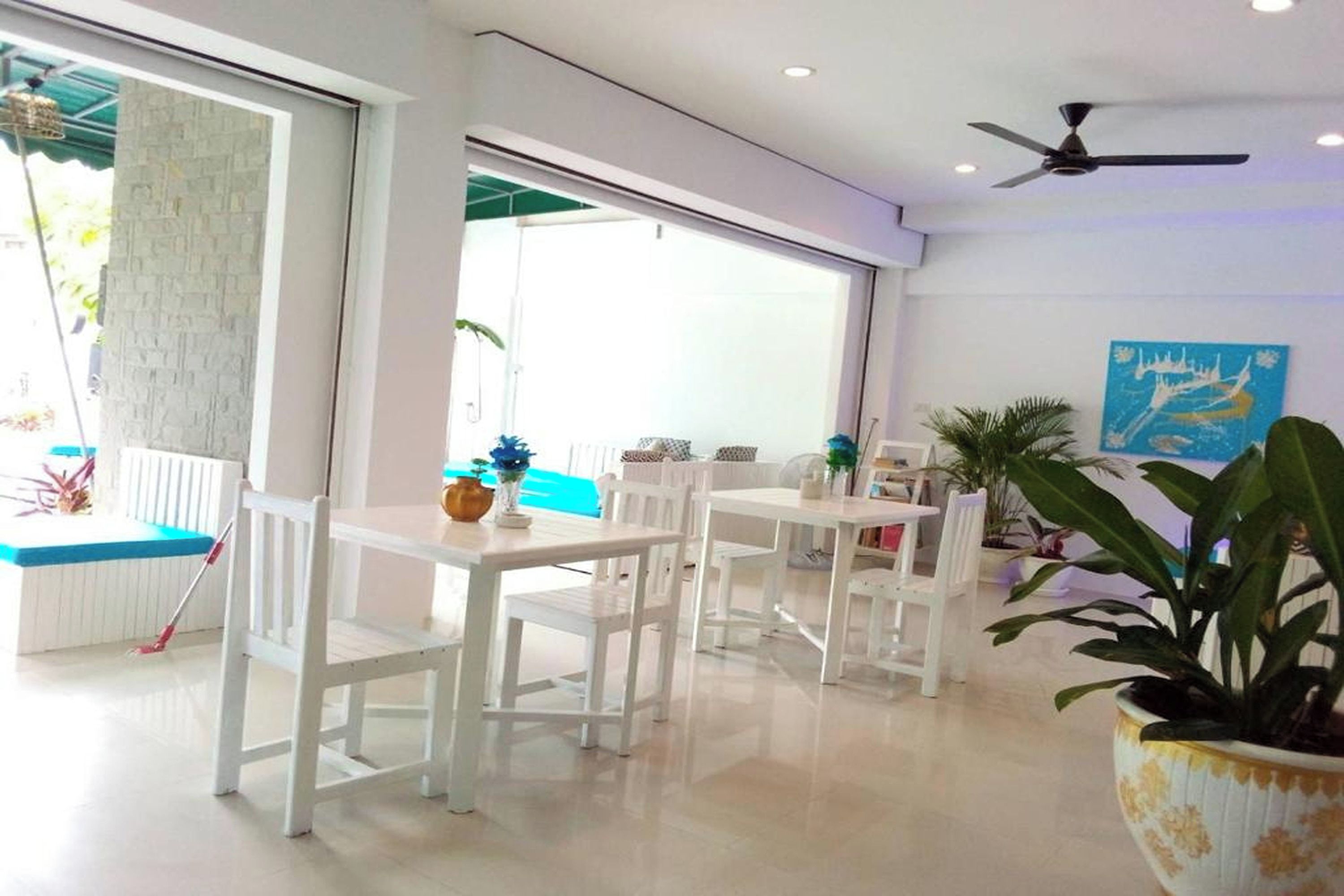A bright, modern room with white furniture, a ceiling fan, and a large window.