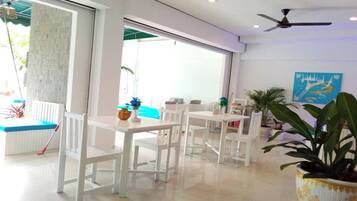 A bright, modern room with white furniture, a ceiling fan, and a large window.