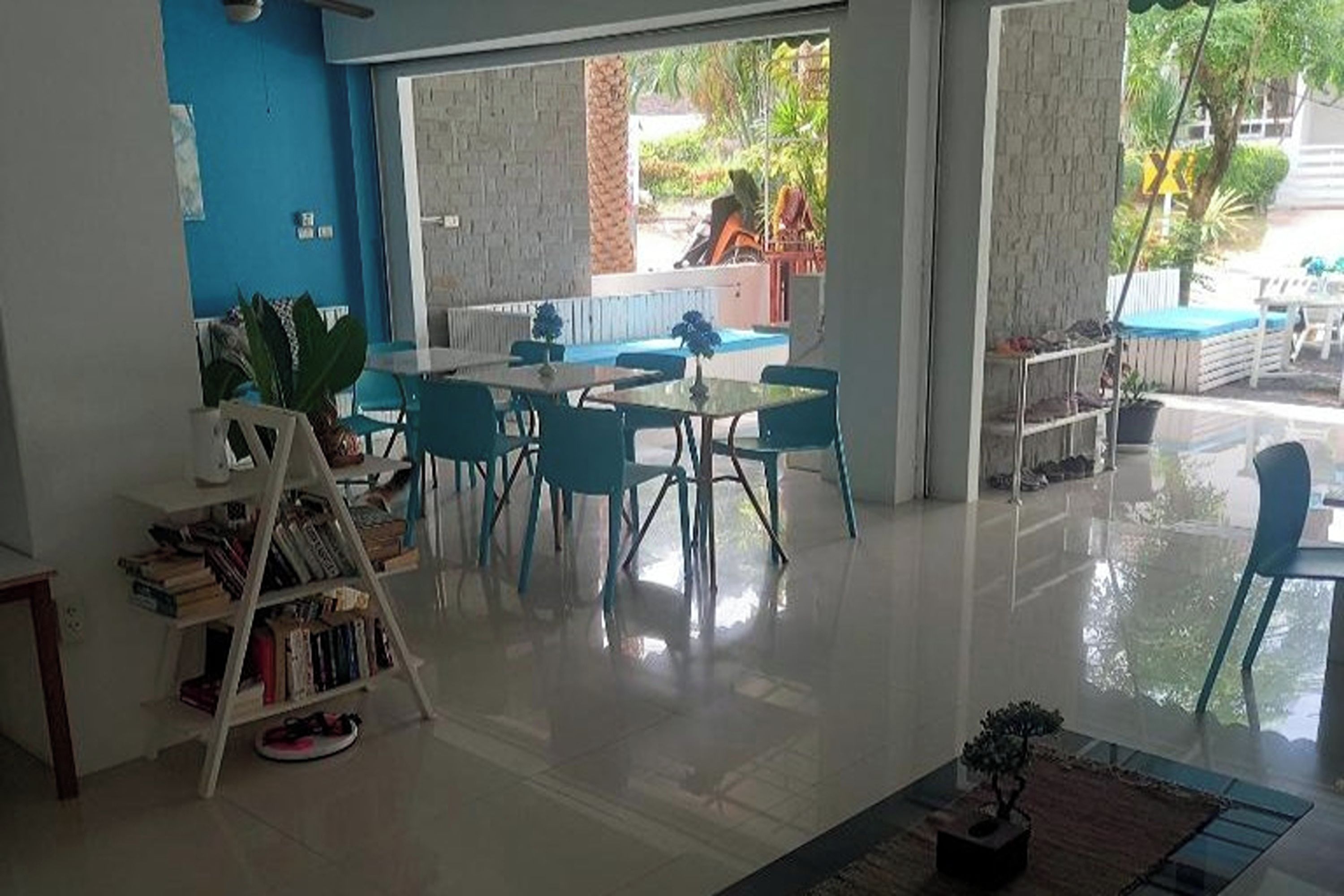 Una habitación amplia con un ventanal grande, una zona de comedor con sillas azules y una estantería.