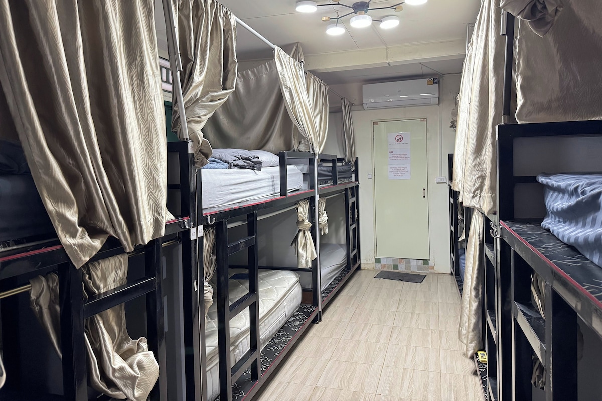 A dormitory room with bunk beds, a ceiling fan, and an air conditioning unit.