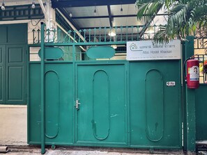 Une porte métallique verte avec une enseigne indiquant l’hôtel Atlas de Khon Saen.