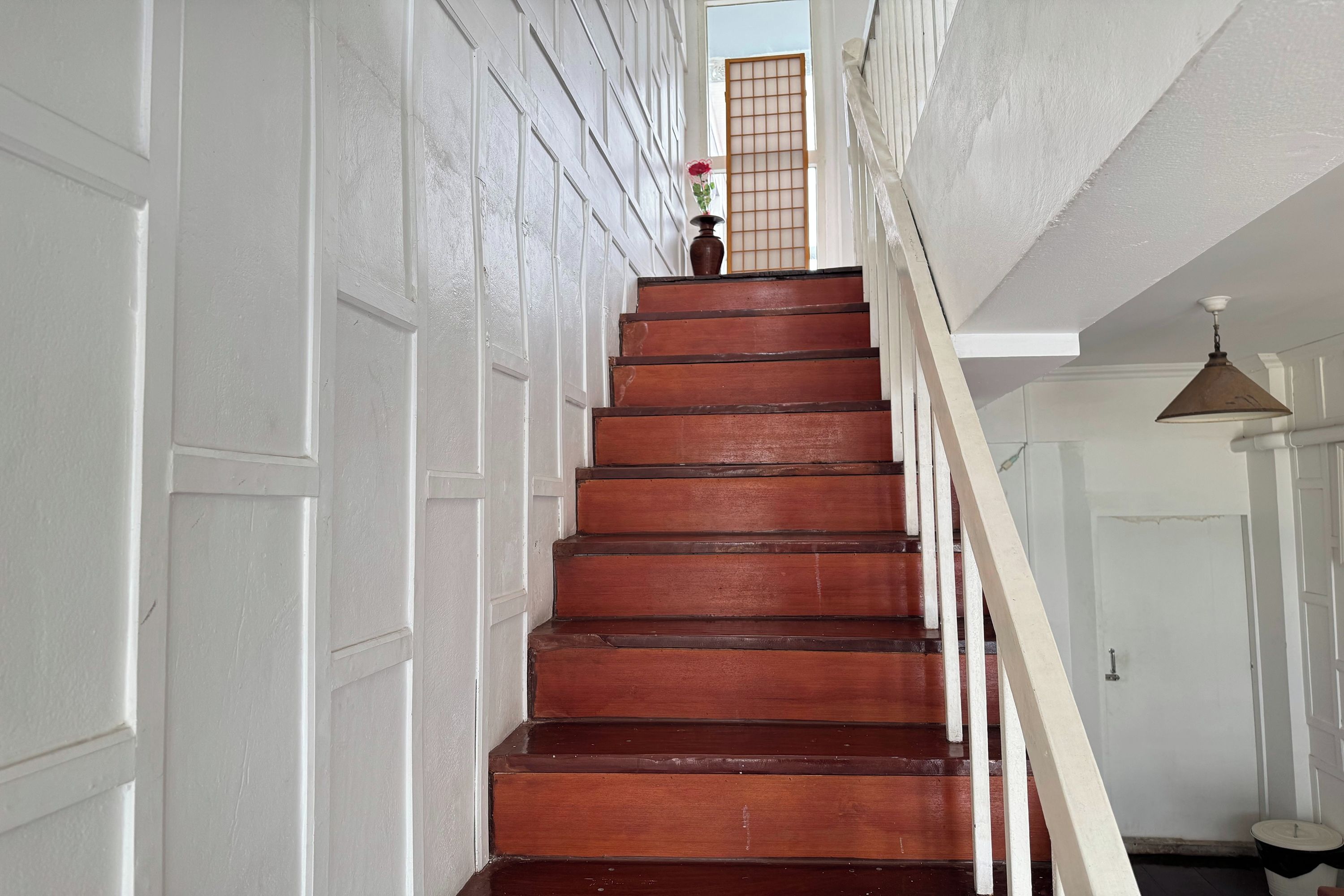 A wooden staircase with white walls and a white door on the left.
