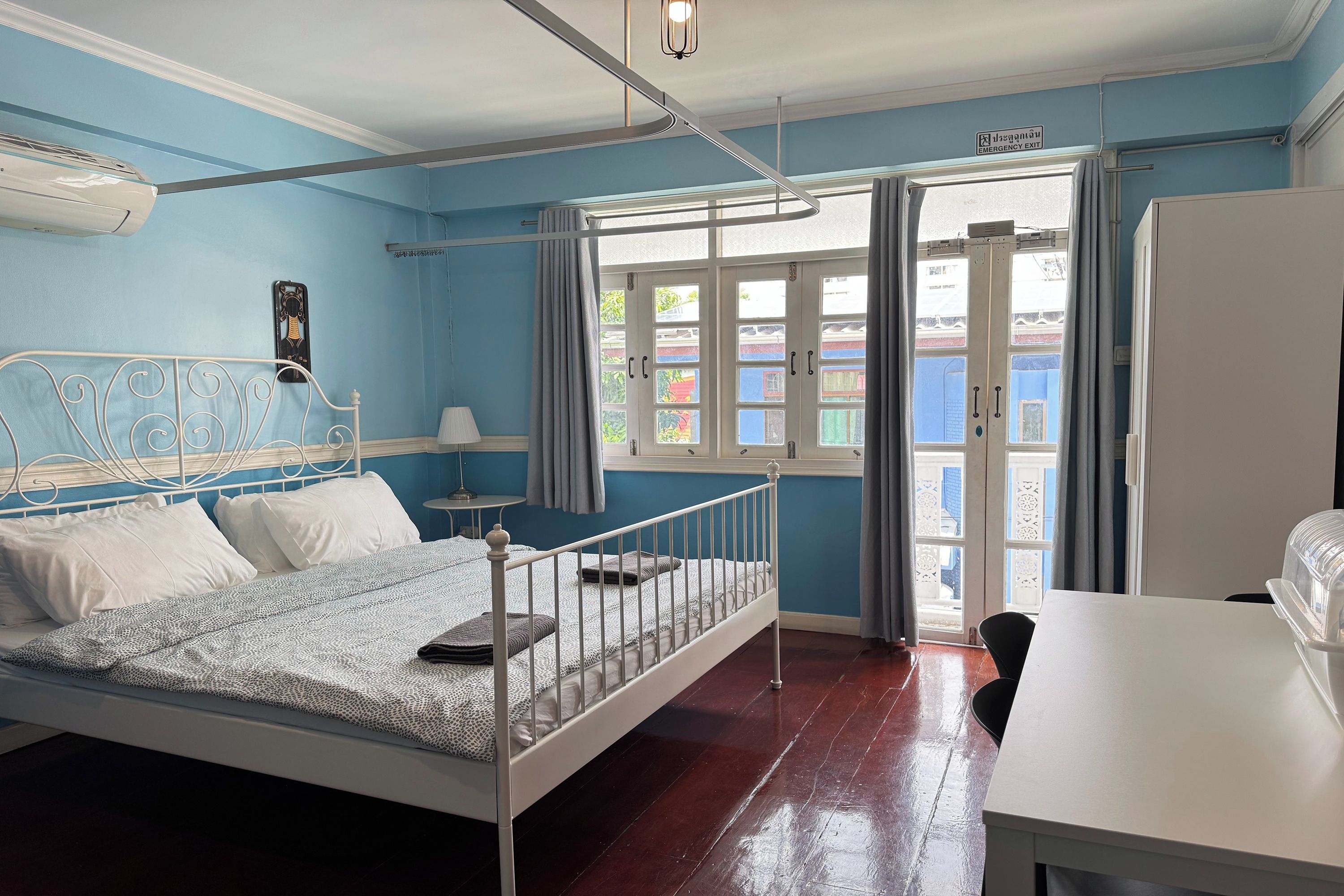 Un dormitorio con cama, mesita de noche, lámpara y vistas al exterior.